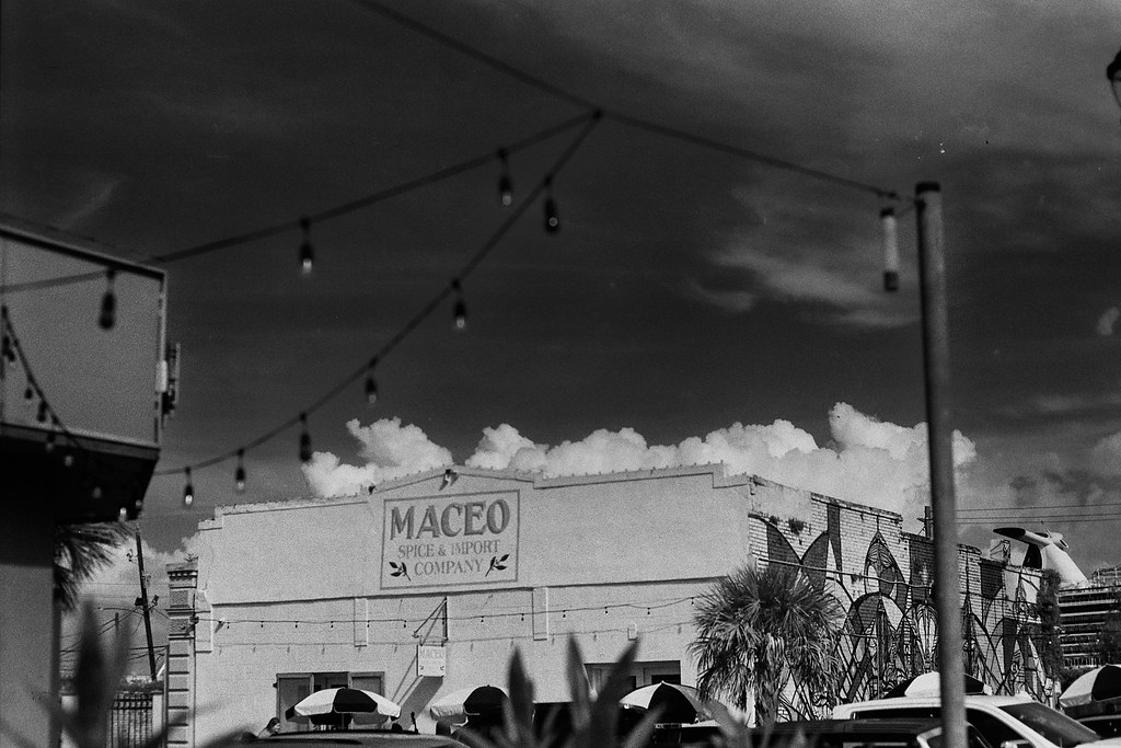 Black-and-white view of Maceo Spice and Import Company beneath storm clouds